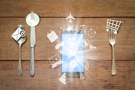 Fork,spoon and knife with smartphone and business application icons on vintage grunge wooden...