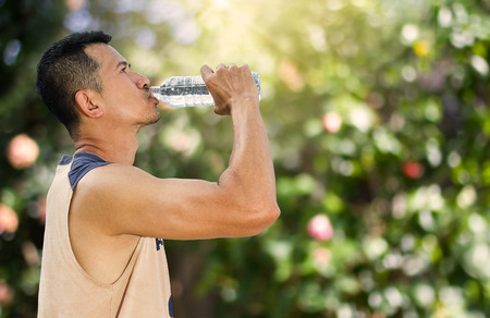 Man drinking water from bottle after running in a parkの写真素材