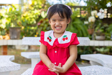 Cute asian baby girl laughing with happiness on blurred nature backgroundの写真素材