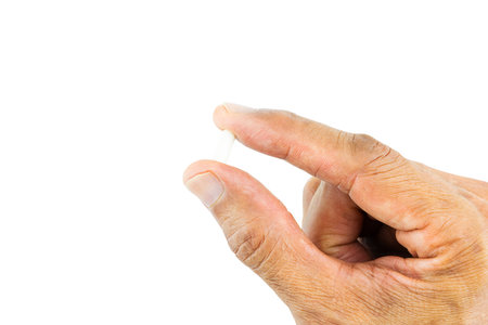 Hand holding pill on white background with clipping pathの写真素材