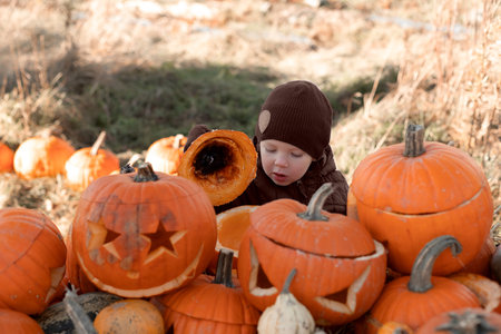 Portrait of a little boy looking at his pumpkin decorated and illuminated for the holiday of halloween at homeの写真素材