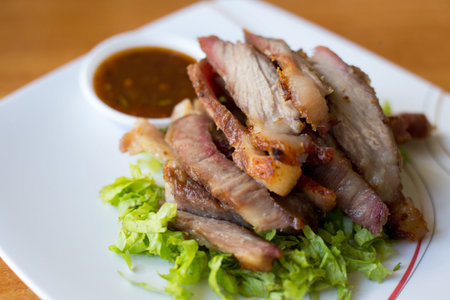 grilled pork sliced on white dish with sauceの写真素材