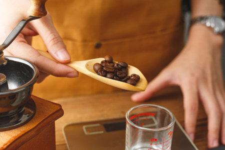 Barista pouring roasted coffee beans in cup to scale and measureの写真素材