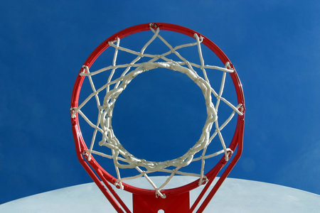 A basketball hoop, net and backboard on a playground, shot from below.