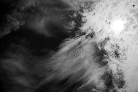 Black and white photo of textured clouds in a dark sky.の写真素材