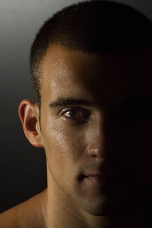 Young tanned man portrait with half face iluminated
