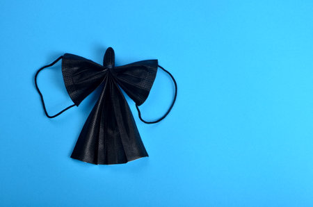 Dark Angel from face protection mask on blue background. COVID-19. Christmas concept on pendemic. Copy space.の写真素材
