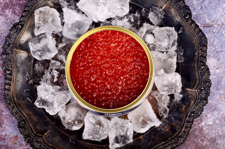 RIGA, LATVIA - december 31, 2020: Opened tin can with Red Salmon Caviar on natural ice in rustic silver plate. Red Lemberg caviar, iron can with red salmon caviarのeditorial素材