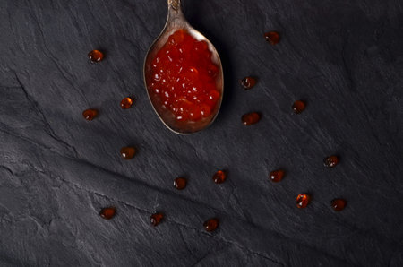 Spoon with red salmon caviar on black stone plate. Copy space.Top view.の写真素材