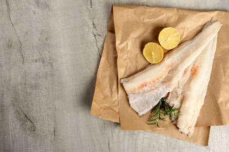 Two Piece of sea fish filet on a paper, decorated with lemon and rosemary, white raw fish filet without a skinの写真素材