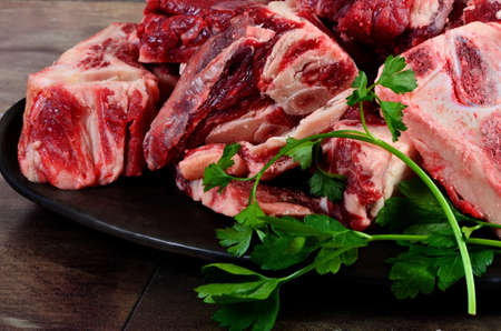 Raw meat with bone on clay plate and brown stone background. Raw meat with beef bone. Beef bone selection for soupの写真素材
