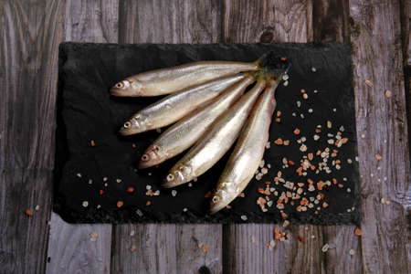 Fresh smelt fish on a black stone plate, Smelt fishes (European smelt) with lemon and green parsley, Group of fresh smelt fishの写真素材
