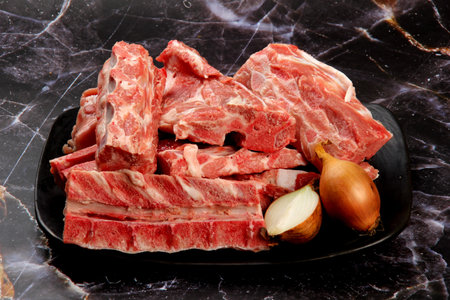 Raw meat with bone on clay plate and luxury marble background. Raw meat with beef bone. Bone selection for soup. Raw meat with bone close-upの写真素材