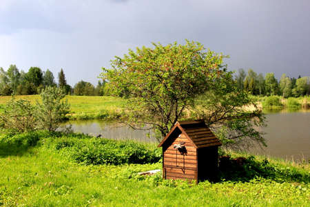Wooden smokehouse in the farm by the pond. Wooden smokehouse in the countryside. Homemade meat smokingの写真素材
