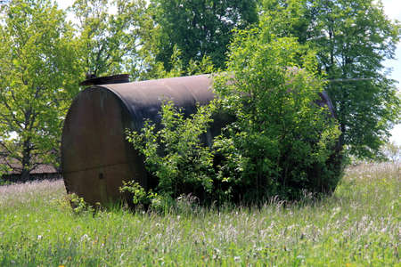 Large metal barrel for water. A metal water barrel stands in the garden.Old rusty Barrel for Irrigation at the Agricultural Fieldの写真素材