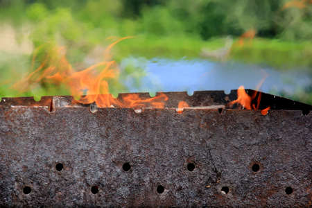 Empty grill grate and fire flame. Fire on charcoal for food grilling. Burning wood in the grillの写真素材