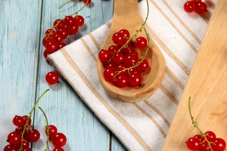 Red currant on blue wooden tablebackground. Cup and jar with fresh red currants (ribes rubrum).