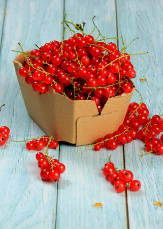 Red currant on blue wooden tablebackground. Cup and jar with fresh red currants (ribes rubrum).