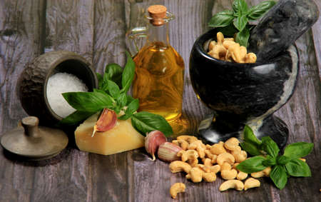 Pesto Ingredients: Fresh Basil, Garlic, Cashew Nuts, Olive Oil and Cheese, copy space, Ingredients for making pesto sauce on a dark wooden background, top view. pesto with Cashewの写真素材