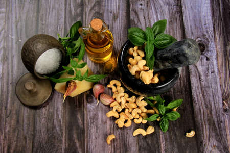 Pesto Ingredients: Fresh Basil, Garlic, Cashew Nuts, Olive Oil and Cheese, copy space, Ingredients for making pesto sauce on a dark wooden background, top view. pesto with Cashewの写真素材