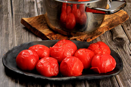 Blanched Red Tomatoes on black clay plate, ready for peeling. Group of Boiled Tomatoesの写真素材