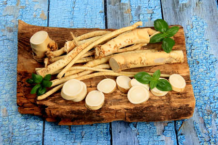 Cut Horseradish roots (Armoracia rusticana taproot) on rustic wooden board. Fresh horseradish.の写真素材