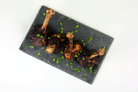 Three fried chicken lollipops on a black stone plate, Fried chicken legs