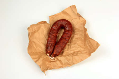 Spanish traditional sausage Chorizo on the crumpled paper on white background. Fresh Spanish chorizo sausageの写真素材
