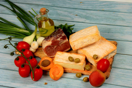 Soft French cheese, Spanish ham and vegetables on a kitchen wooden board. blue rustic wooden backgroundの写真素材