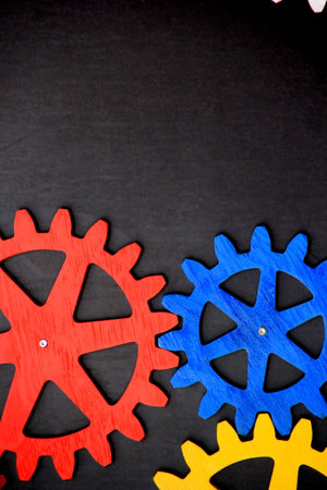 Colorful wooden gears on a black background. Space for text. A toy for children's developmentの写真素材