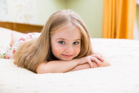 Adorable little girl awaked up in her bedの写真素材