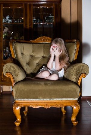 Abused little girl covering here face while crying. Concept photo of child abuse, social issuesの写真素材