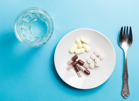 A fork with a pile of medicines and a glass of water.の素材 [FY310113062255]