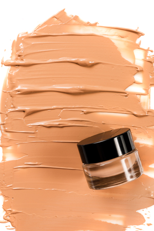 A glass jar of foundation for a face with a sample of the product itself. Cosmetic concept.の写真素材