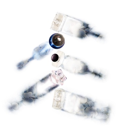 A collection of perfume bottles with blue fresh flowers in the shadows, aimed in different directions. View from above.の写真素材