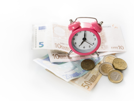 Green alarm clock on the background of europrints and coins. Isolated on white background.の写真素材