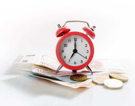 Green alarm clock on the background of europrints and coins. Isolated on white background.の写真素材