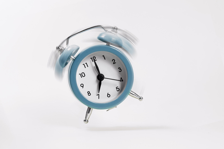 The blue morning alarm rings and jumps on a gray background.の写真素材