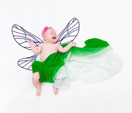 Laughing baby girl wrapped in fabric on cloud with painted butterfly wingsの写真素材