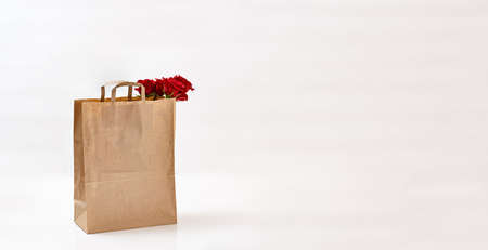 Beautiful roses in paper bag on a light background. Free space for text. Mockup for your design on the package. concept for mothers day and valentines dayの写真素材