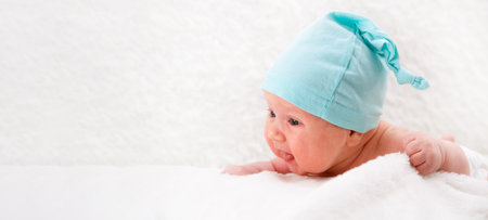a one-month-old baby in a blue cap lies on his stomach and looks at the world. Family concept. Mockup on the header. Copycpaceの写真素材
