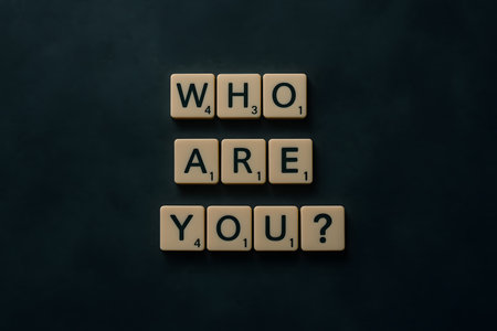 A studio shot featuring Scrabble tiles spelling out a question about identity, set against a dark backdrop, prompting self-reflection.の素材