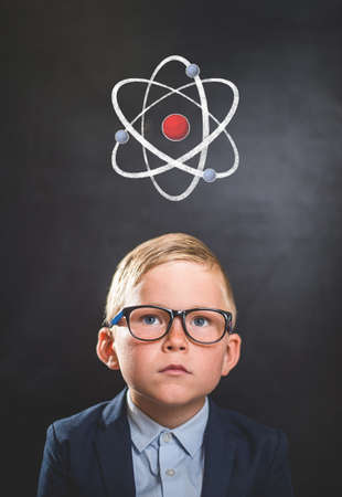 Kid and atom against blackboard. Explore this great world. Back to school.の写真素材