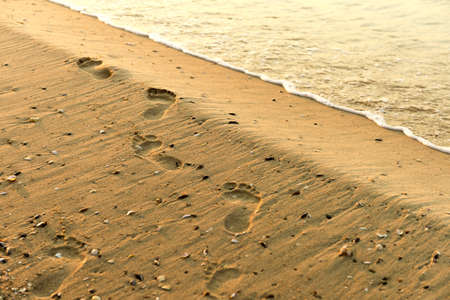 Foot prints at sand in sunrise on sea beach. Steps on sand. Sun riseの写真素材