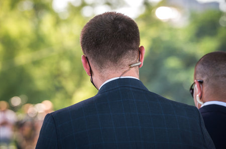 Security officer use radio. bodyguard standing and listening message with security earpiece on helipad. Security guard man on event. Secret service. Private guard in crowd. Team work secret missionの写真素材