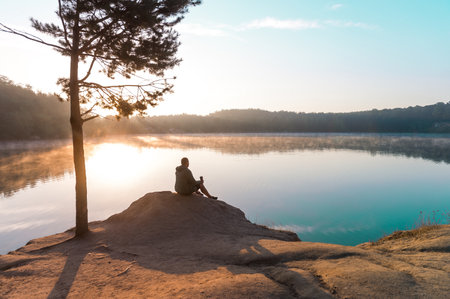 Man traveler relaxing alone in mountains travel lifestyle concept bright morning nature landscape on background. Lake and mountains. inspiration concept, enjoy life.の写真素材