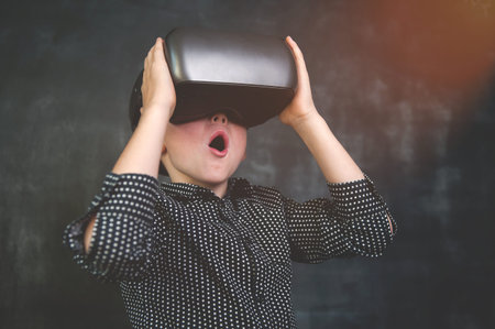 Boy with open mouth in virtual reality helmet. Kid in VR headset. School child discover the planet