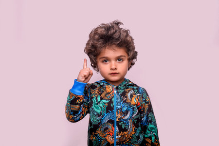 Smart little boy pointing up and looking at camera. Clever hispanic child has great idea. Kindergarten kid ready to go to school. Back to school concept. rules of conductの写真素材