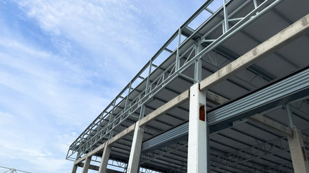 Side view of steel roof truss and concrete beam structure in modern industrial warehouse...