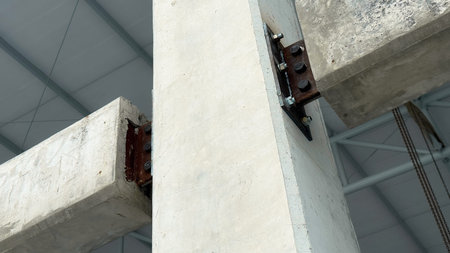 Structural connection of concrete beams to a column with steel plate and bolts, showing engineering...